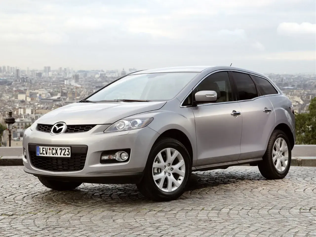 Srebrna Mazda CX7 na tle paryskiego krajobrazu. Stylowy SUV gotowy na miejskie przygody.
