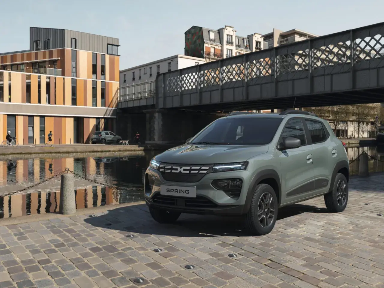 Dacia Spring Electric, miejski samochód elektryczny, zaparkowany nad kanałem w słoneczny dzień.