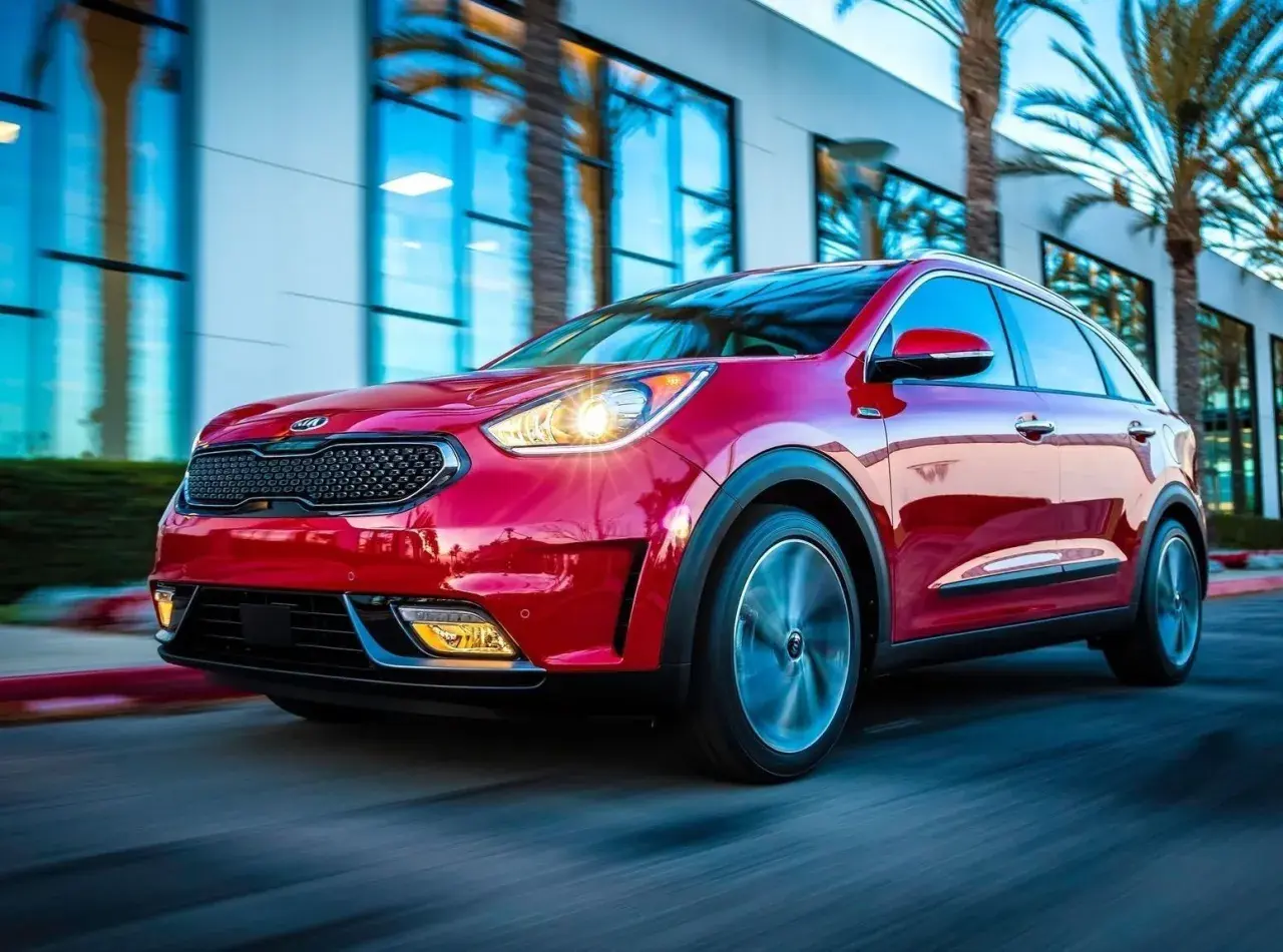 Czerwony Kia Niro w ruchu. Choć auto wygląda dynamicznie, warto pamiętać o jego potencjalnych wadach, np. ograniczonym zasięgu w wersji hybrydowej.
