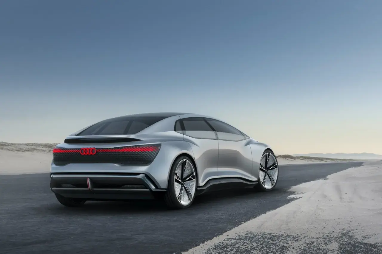 Srebrny Audi A9, futurystyczny koncept, jedzie po pustej drodze.