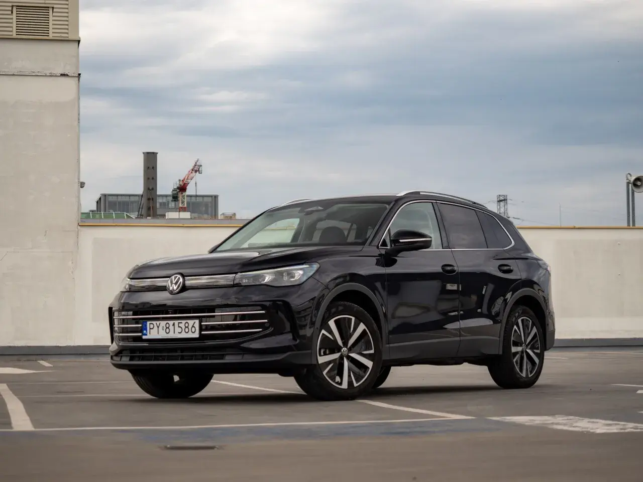Czarny Volkswagen Tiguan 2020 na parkingu, z widocznym fragmentem miasta w tle.