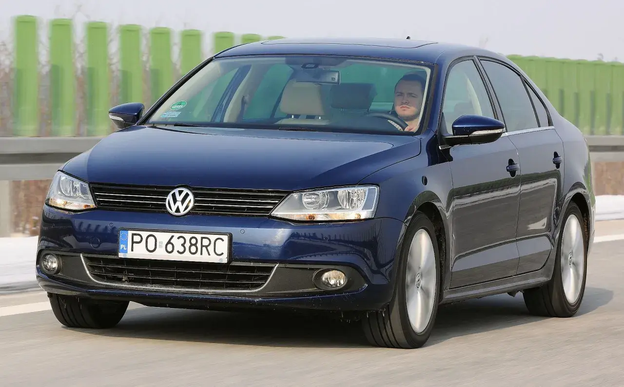 Ciemnoniebieski VW Jetta MK6 jedzie po autostradzie. Kierowca patrzy przed siebie.