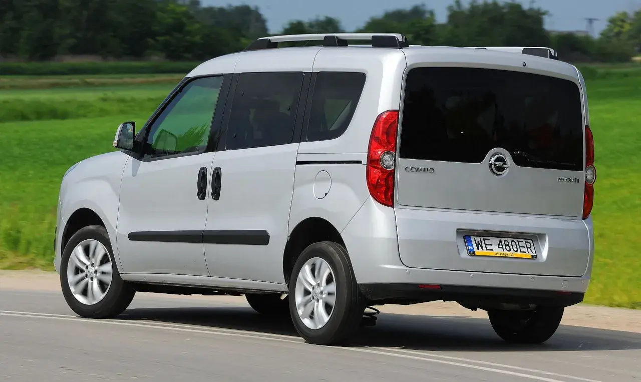 Srebrny Opel Combo C w ruchu, z tyłu widoczny bagażnik dachowy i przyciemniane szyby.