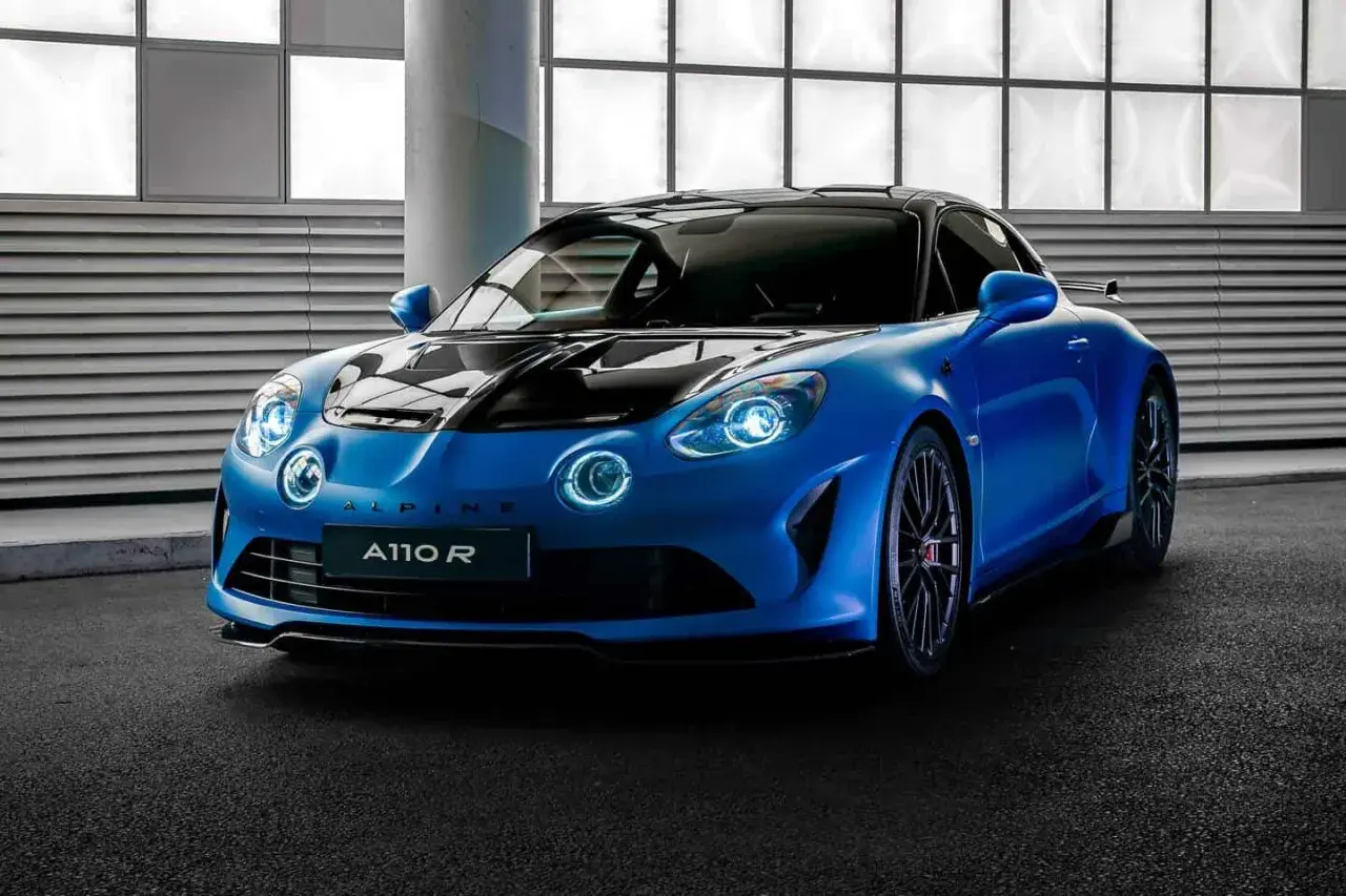 Niebieski Alpine A110 R z czarną maską i dachem, gotowy do jazdy po torze.