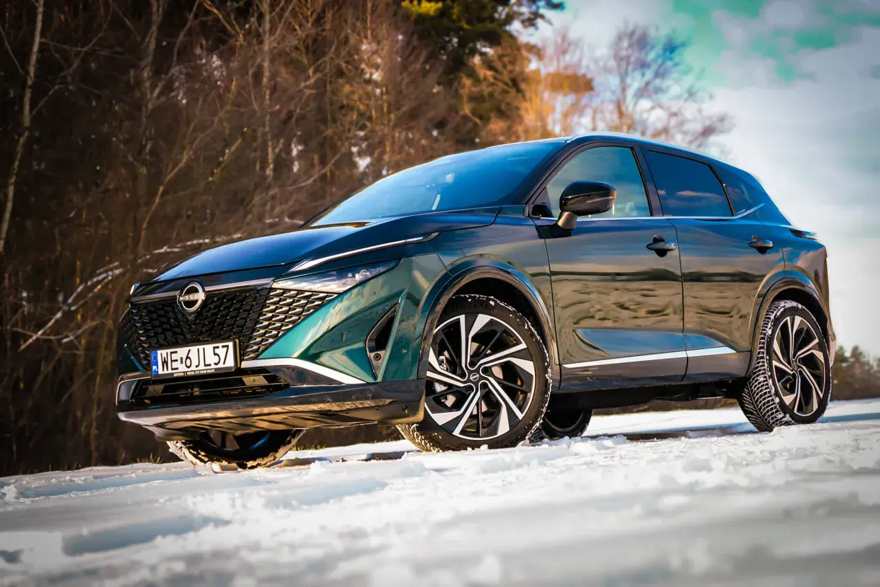 Zielony Nissan Qashqai na śniegu. Wiele osób szuka nissan qashqai opinie forum przed zakupem.
