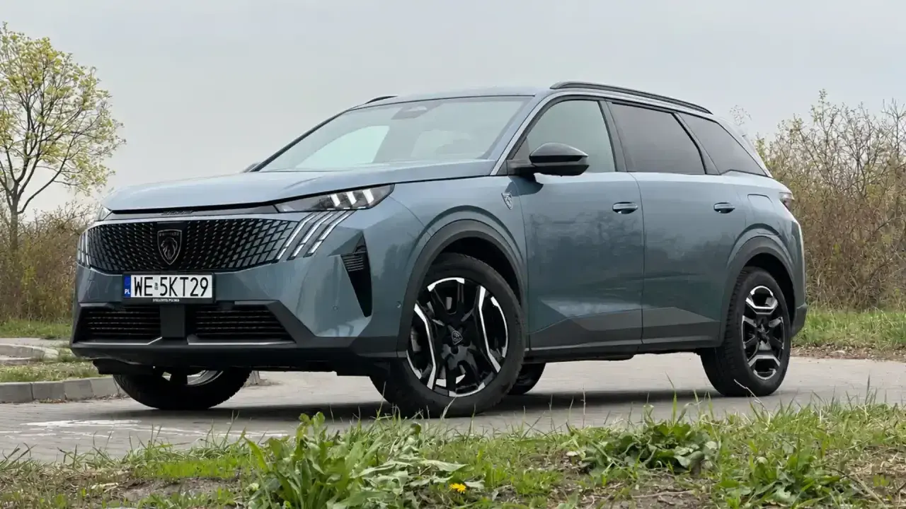 Nowy Peugeot 5008 w kolorze szarym, z czarnymi felgami i nowoczesnym grillem. Wiele osób szuka peugeot 5008 opinie przed zakupem.
