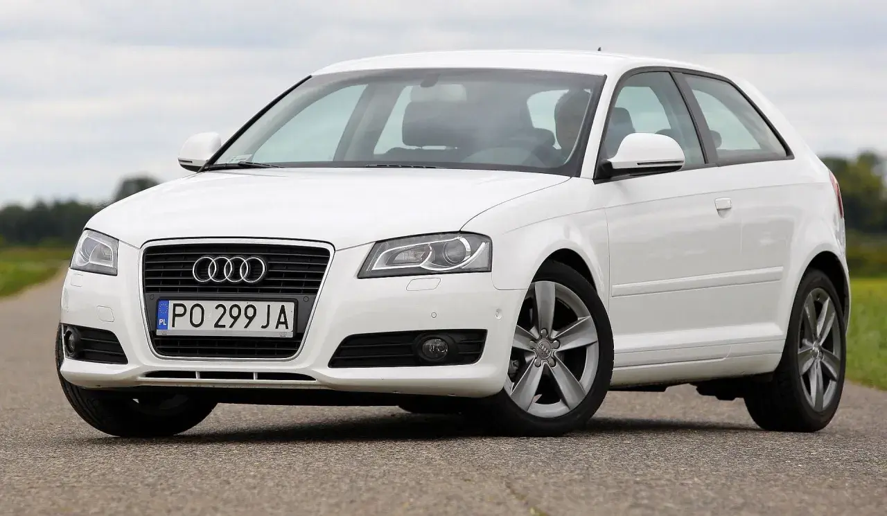Białe Audi A3 2004 na drodze, z widocznym grillem i tablicą rejestracyjną PO 299 JA.