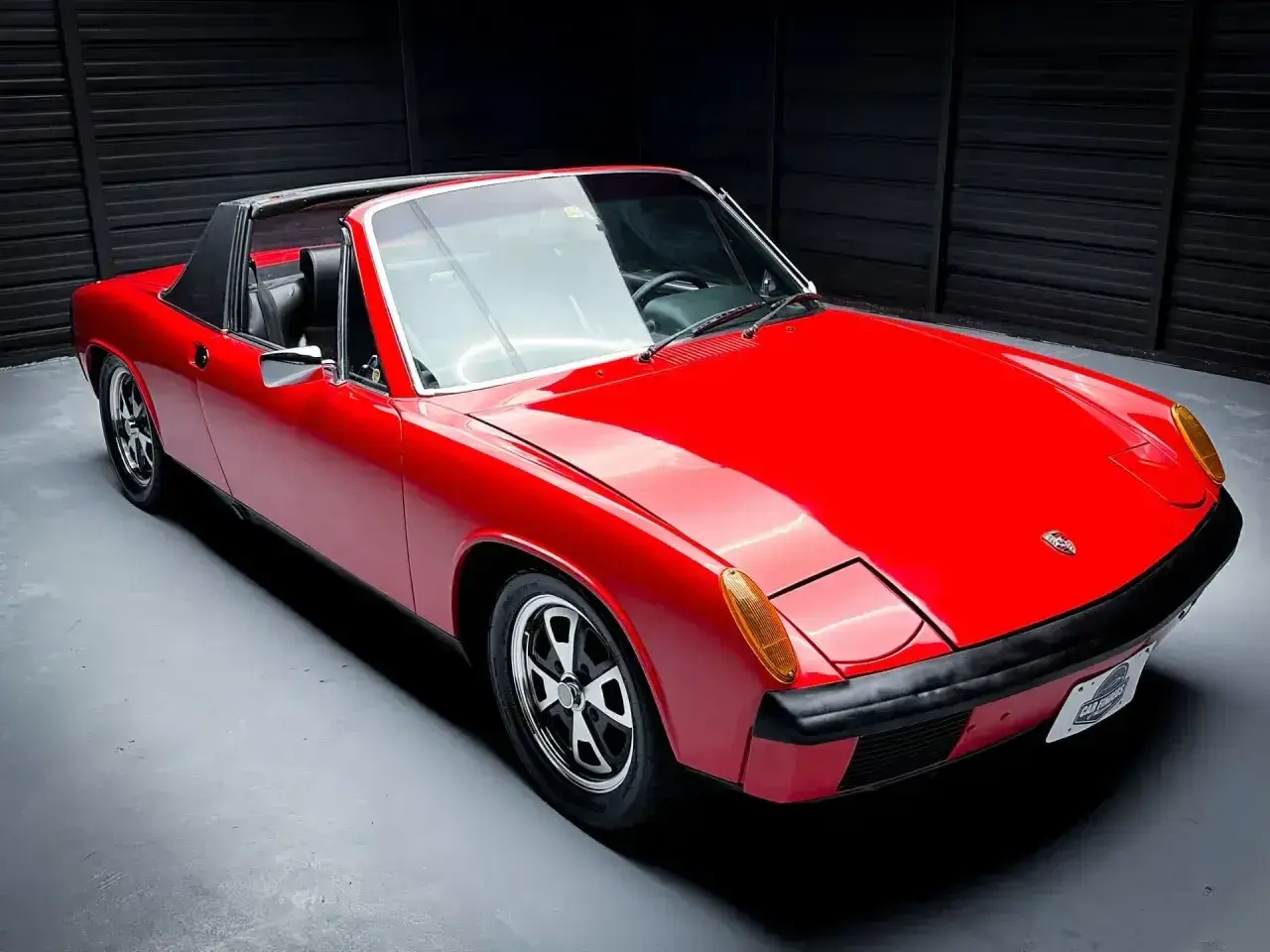 Czerwony Porsche 914 z czarnym dachem targa, gotowy do jazdy po krętych drogach.