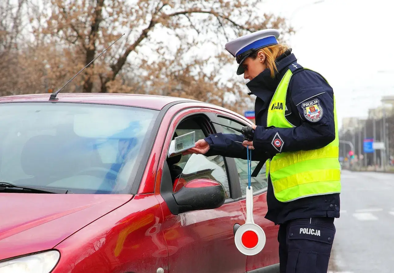 Policjantka kontroluje dokumenty kierowcy. Czy trzeba mieć przy sobie dowód rejestracyjny? Tak, w Polsce jest to obowiązkowe.