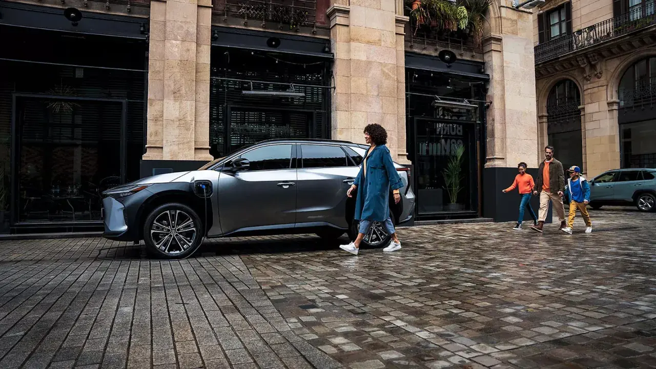 Rodzina idzie obok ładowanego elektrycznego SUV-a Toyoty. EV mode Toyota co to? To przyszłość motoryzacji.