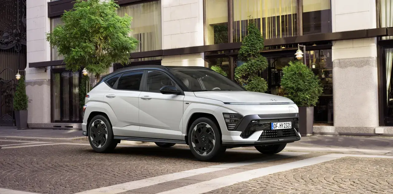 Biały Hyundai Kona N Line na tle eleganckiego budynku. Sprawdź aktualną hyundai kona cena i wybierz swój wymarzony model.