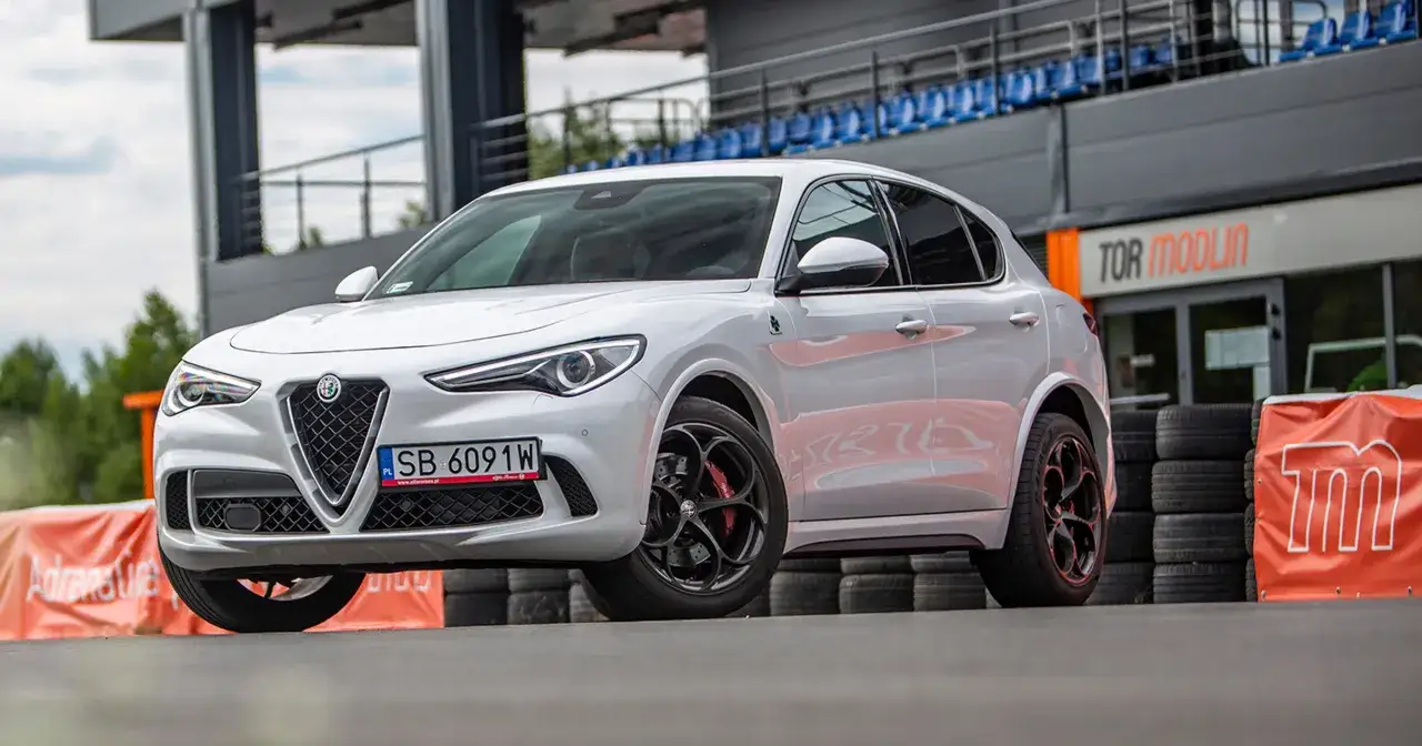 Białe Alfa Romeo Stelvio Quadrifoglio na torze wyścigowym, gotowe do jazdy.