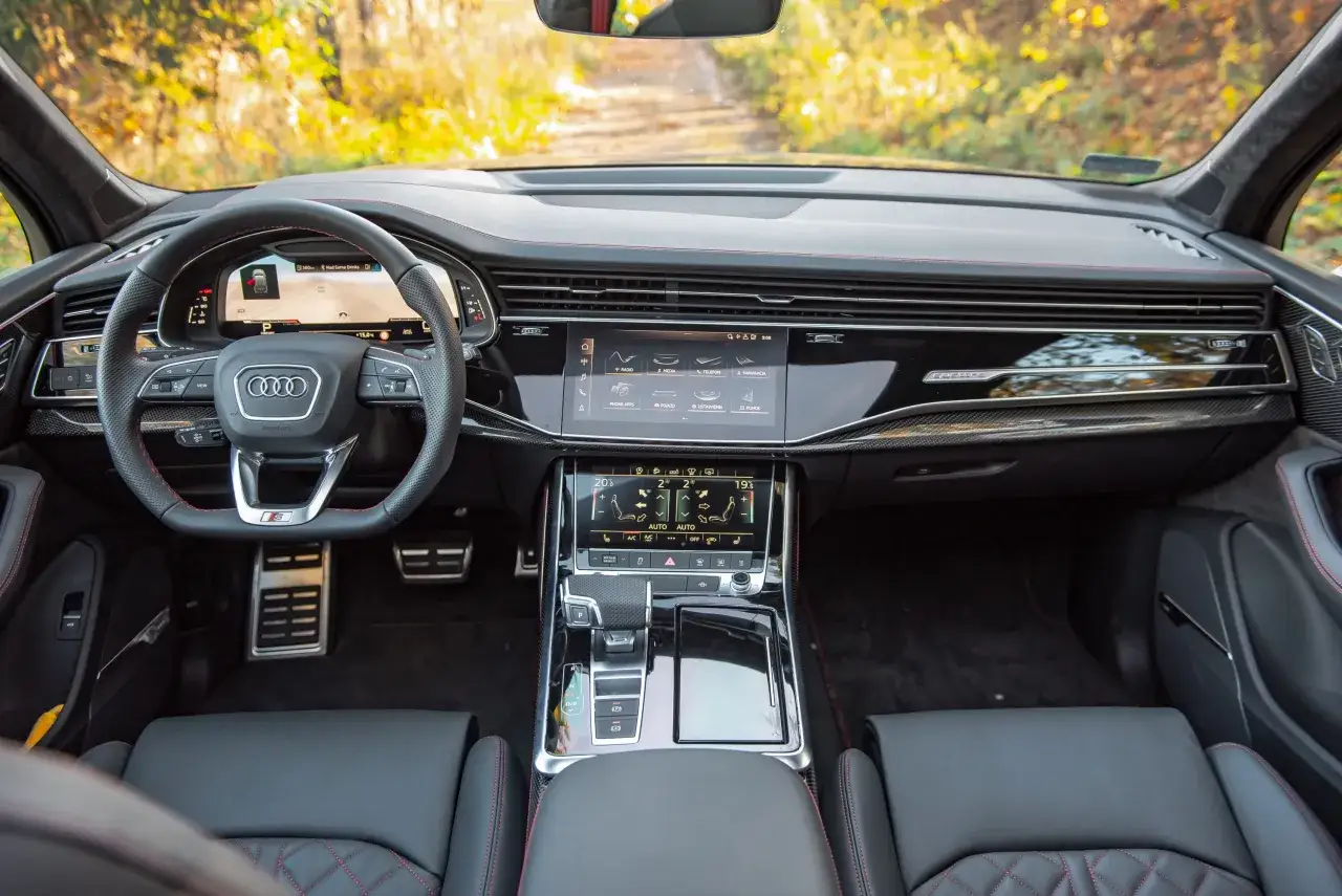 Wnętrze nowego Audi Q7 z cyfrowymi ekranami, kierownicą i eleganckimi detalami.