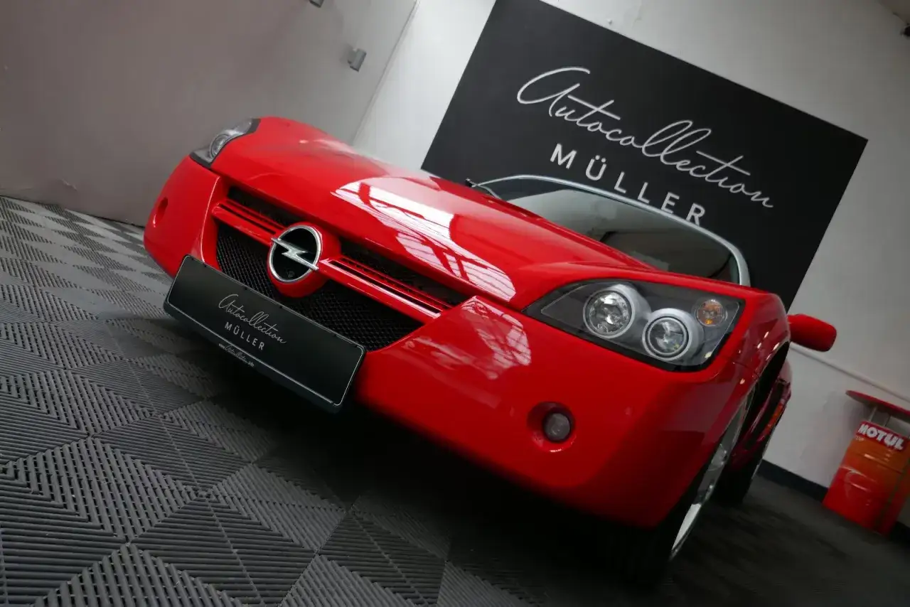 Czerwony Opel Speedster błyszczy na tle czarnej tablicy z napisem 
