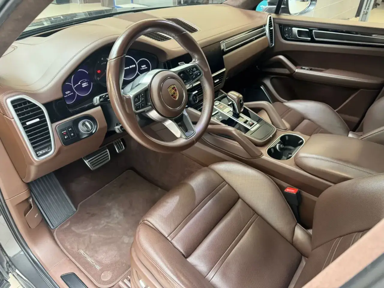Wnętrze Porsche Cayenne GTS w brązowej skórze. Widoczna kierownica, deska rozdzielcza, fotele i konsola środkowa.