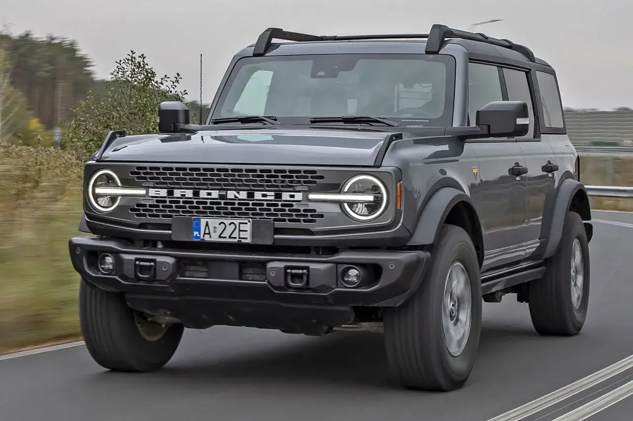 Szary Ford Bronco, jeden z wielu modeli Forda, jedzie po drodze.