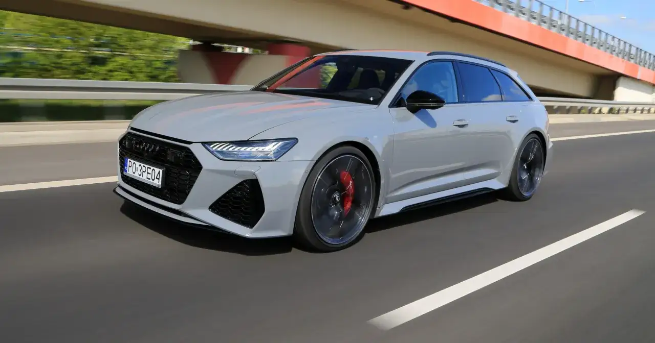 Szary Audi RS6 Avant pędzi po drodze, podziwiając widoki pod mostem.