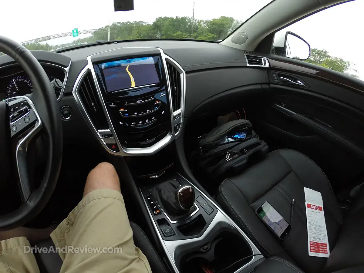 Wnętrze Cadillaca SRX z nawigacją GPS, telefonem i torbą na siedzeniu pasażera.