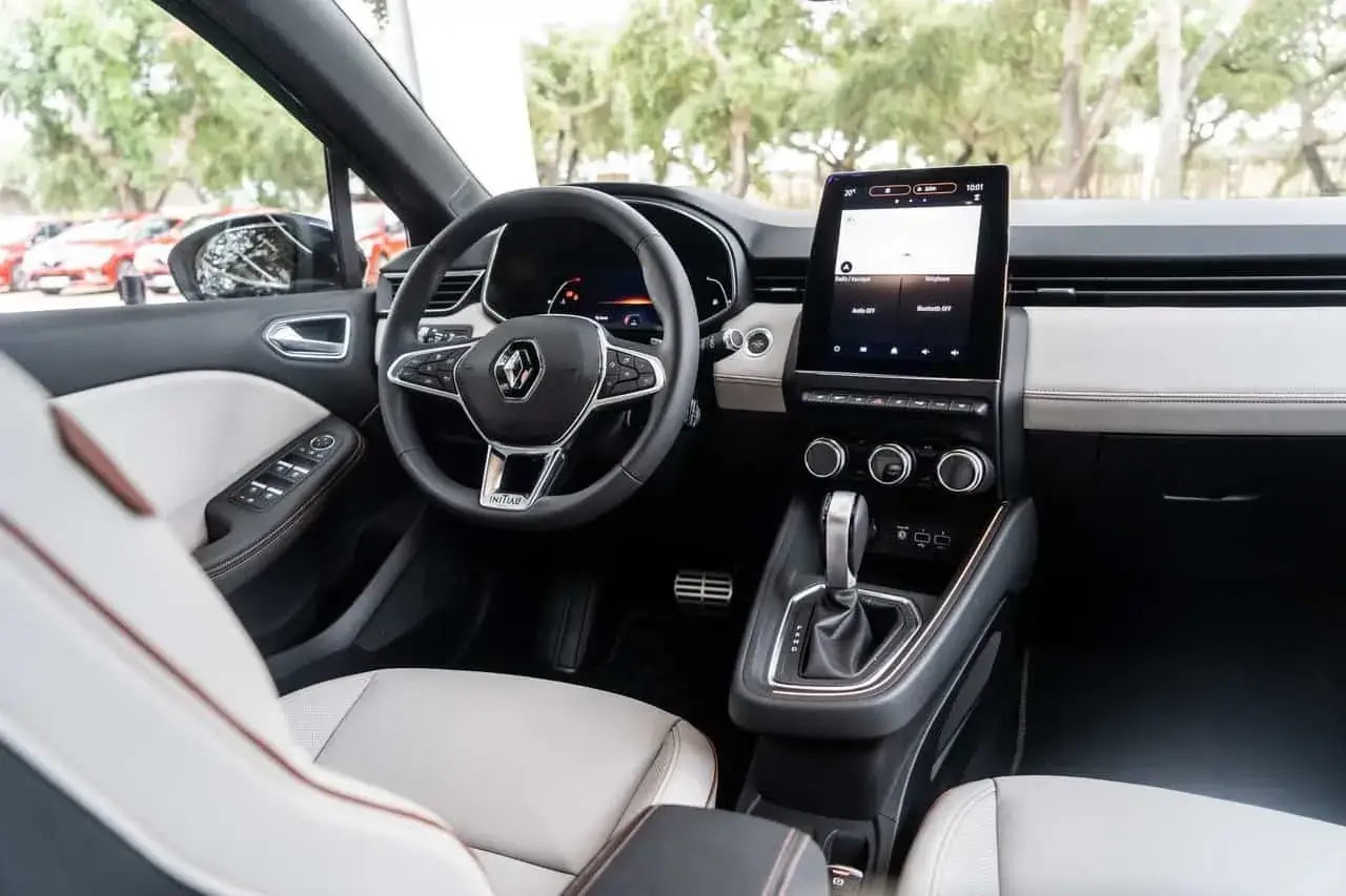 Wnętrze Renault Initiale: skórzana tapicerka, nowoczesny ekran multimedialny i kierownica z logo.