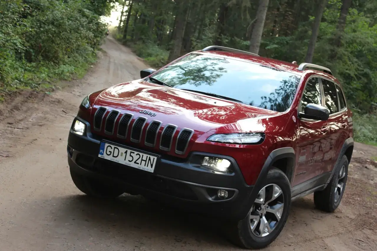 Czerwony Jeep Cherokee Trailhawk na leśnej, piaszczystej drodze. Gotowy na przygodę.