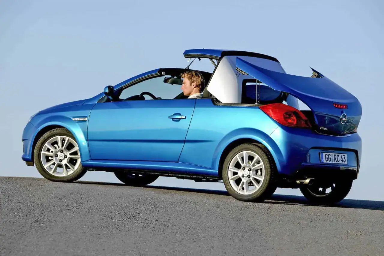 Niebieski Opel Tigra cabrio z otwartym dachem, kierowca w jasnej koszuli.