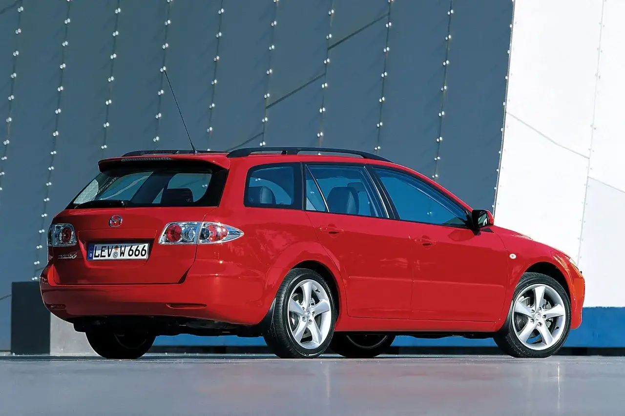 Czerwona Mazda 6 GG kombi stoi przed nowoczesnym budynkiem.