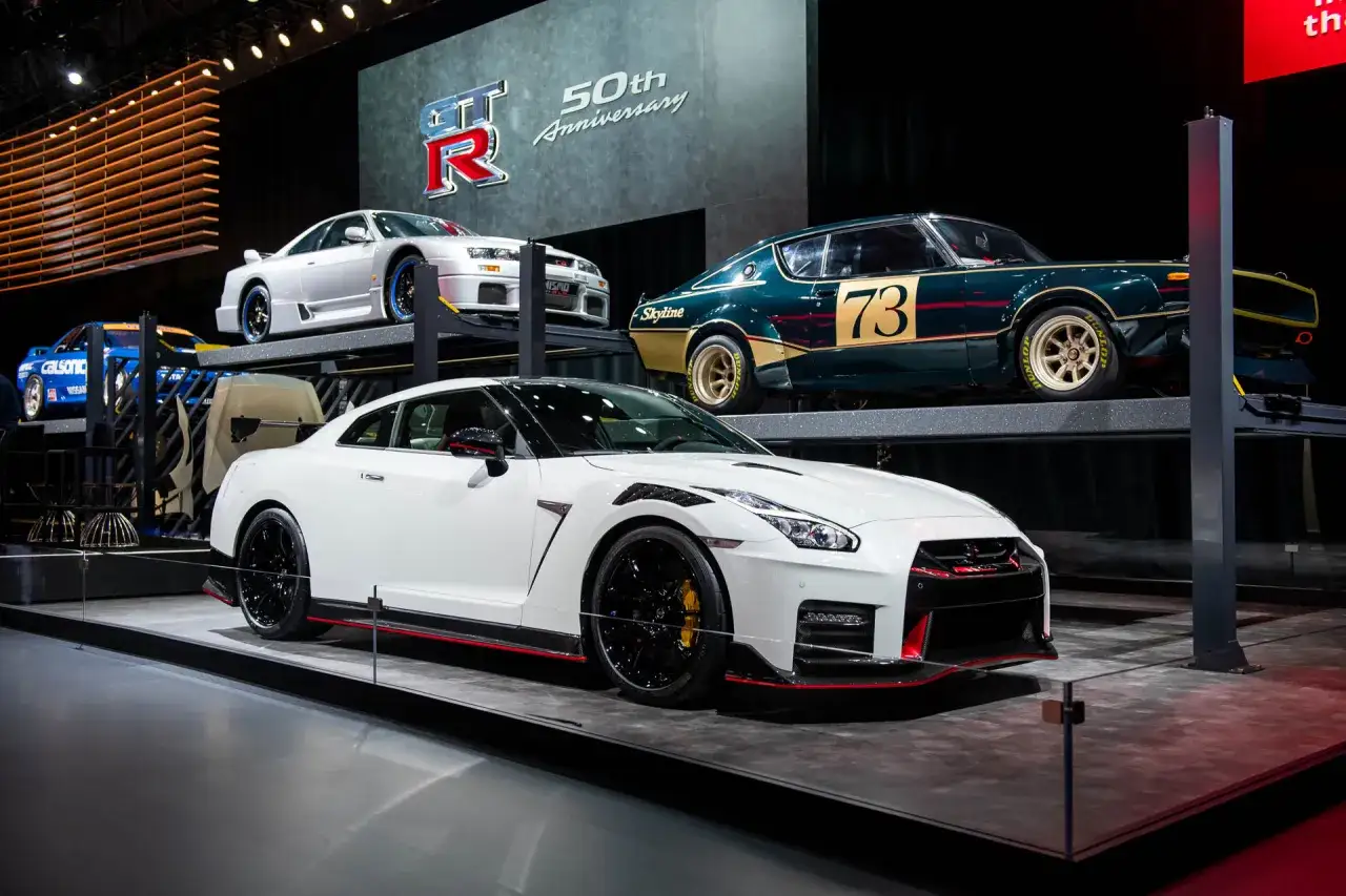 Biały Nissan GT-R Nismo obok klasycznych modeli Skyline na wystawie z okazji 50-lecia.