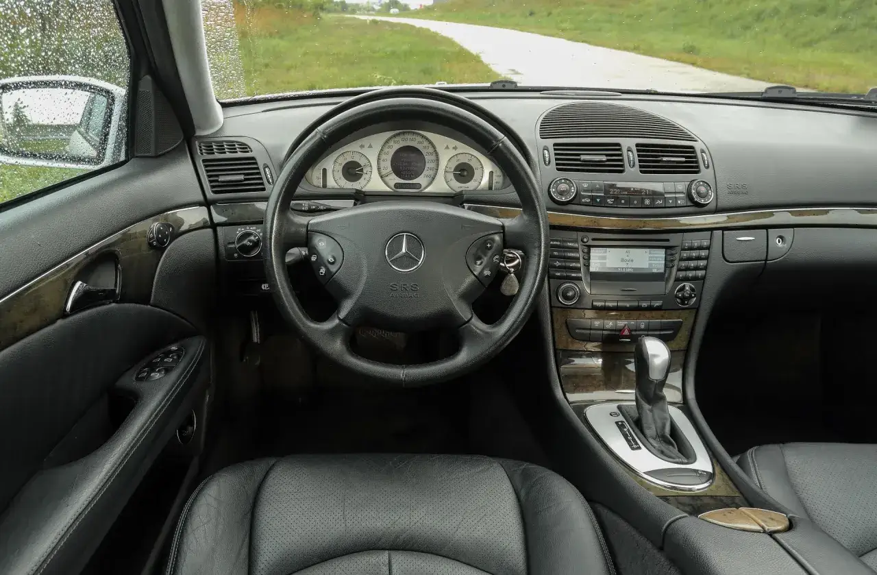 Wnętrze w211 mercedes z czarną skórzaną tapicerką, drewnianymi wstawkami i kluczykiem w stacyjce.