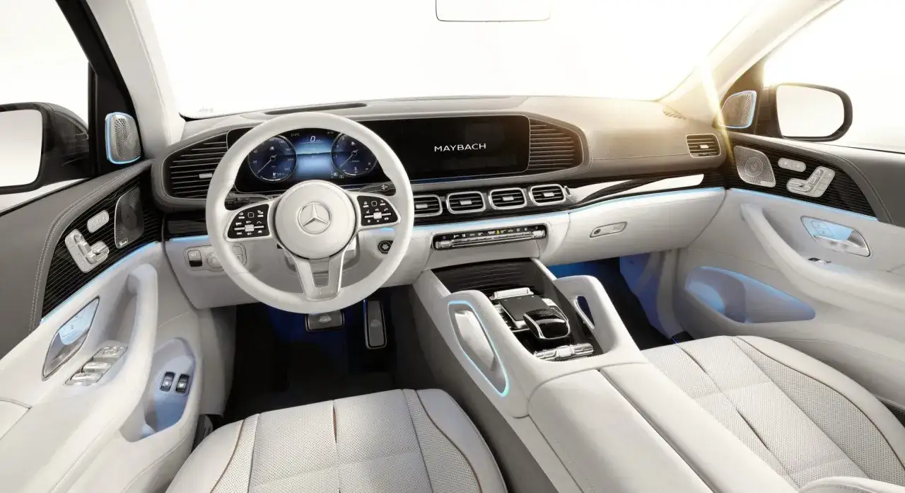 Wnętrze luksusowego gls maybach z białymi skórzanymi fotelami, nowoczesnym kokpitem i ambientowym oświetleniem.