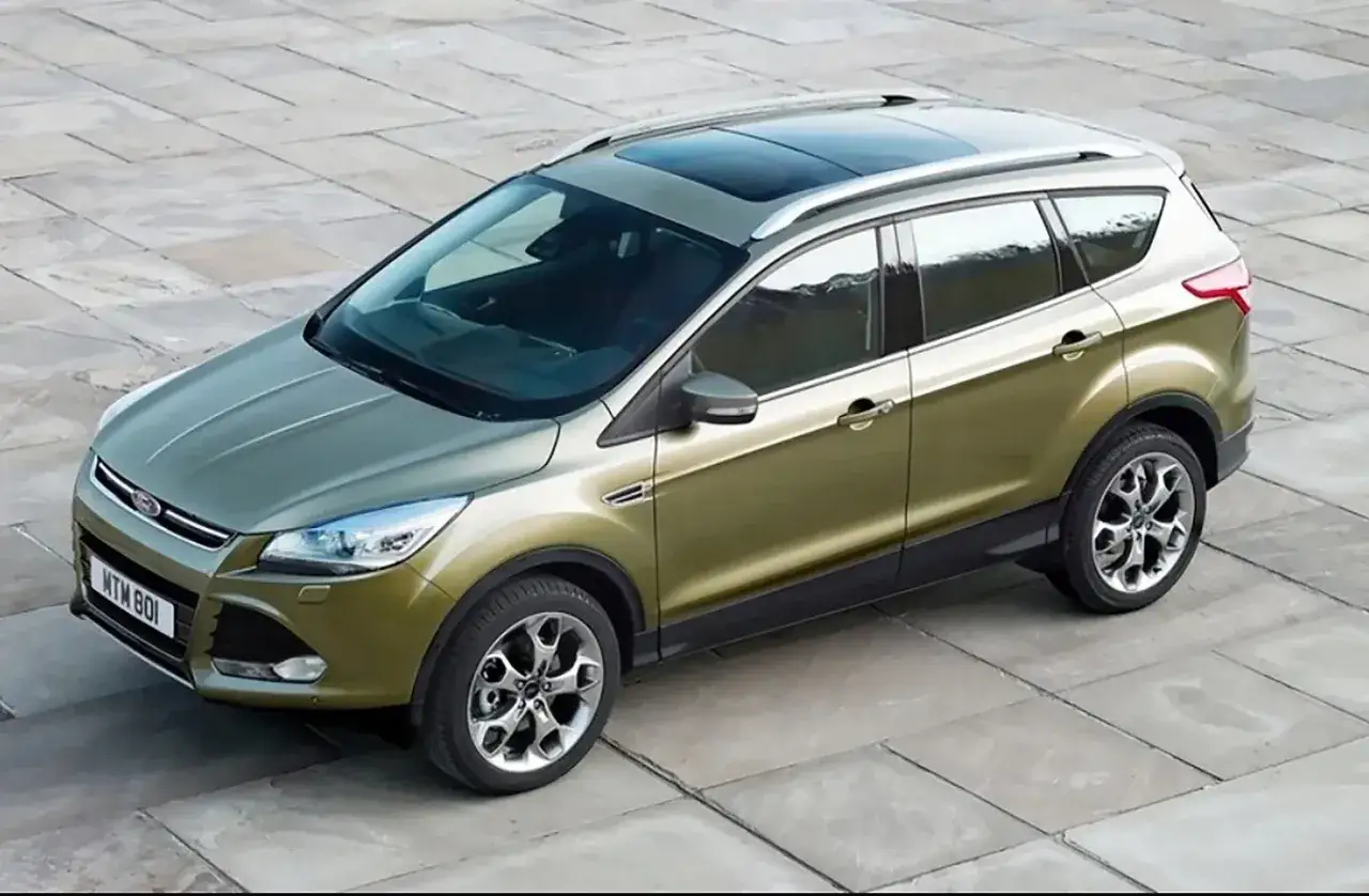 Złoty Ford Kuga 2 z panoramicznym dachem stoi na betonowym placu.