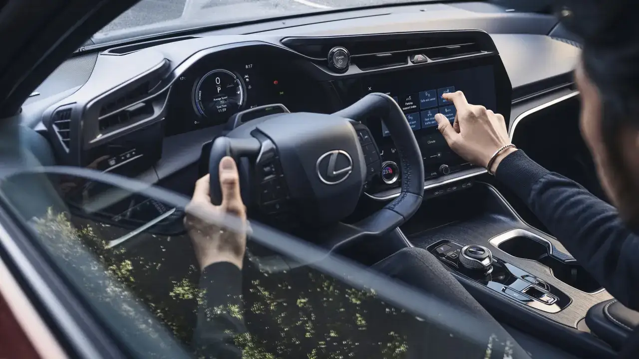 Wnętrze nowego Lexus RZ. Kierowca obsługuje ekran dotykowy, wybierając funkcje pojazdu.