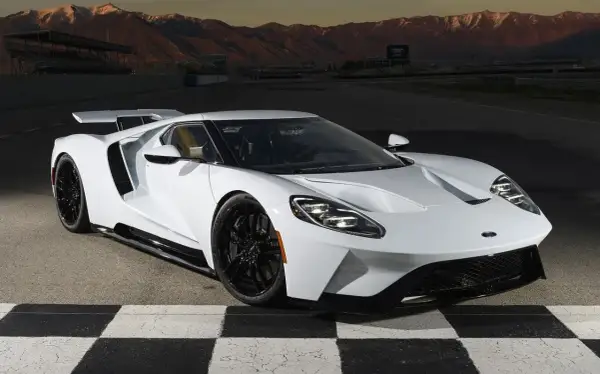 Biały Ford GT na torze wyścigowym, z górami w tle. Marzenie o osiągach i stylu, które wpływa na ford gt cena.