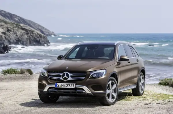 Brązowy, używany Mercedes GLC z salonu na tle morskiego krajobrazu. Idealny na wakacyjne wyprawy.