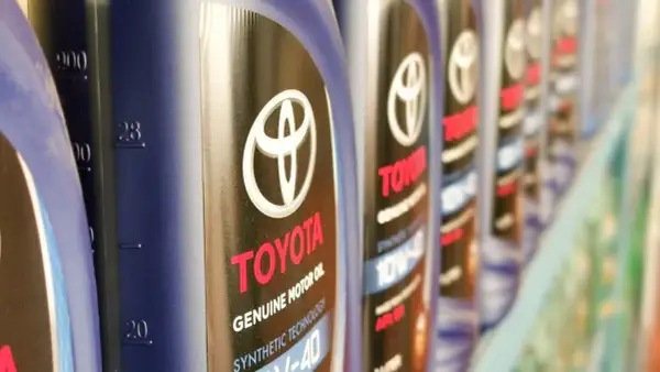 Rząd butelek oryginalnego oleju Toyota. Kto produkuje? Toyota, znana marka samochodów, produkuje również wysokiej jakości oleje silnikowe.