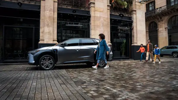 Rodzina idzie obok ładowanego elektrycznego SUV-a Toyoty. EV mode Toyota co to? To przyszłość motoryzacji.